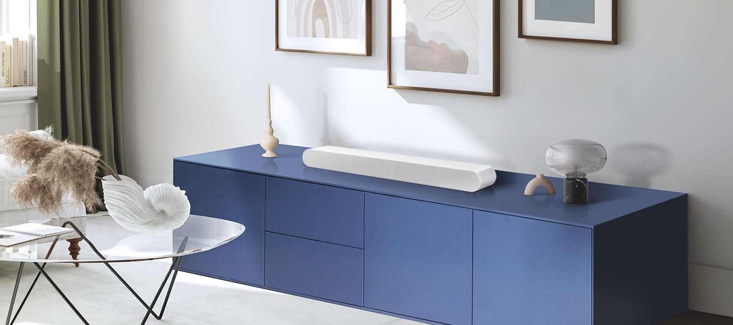 A modern living room with decor such as wall art and figurines. A Soundbar is placed on top of a sideboard.