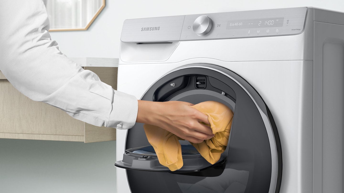 Extra laundry is added into the open Add Wash door by hand.