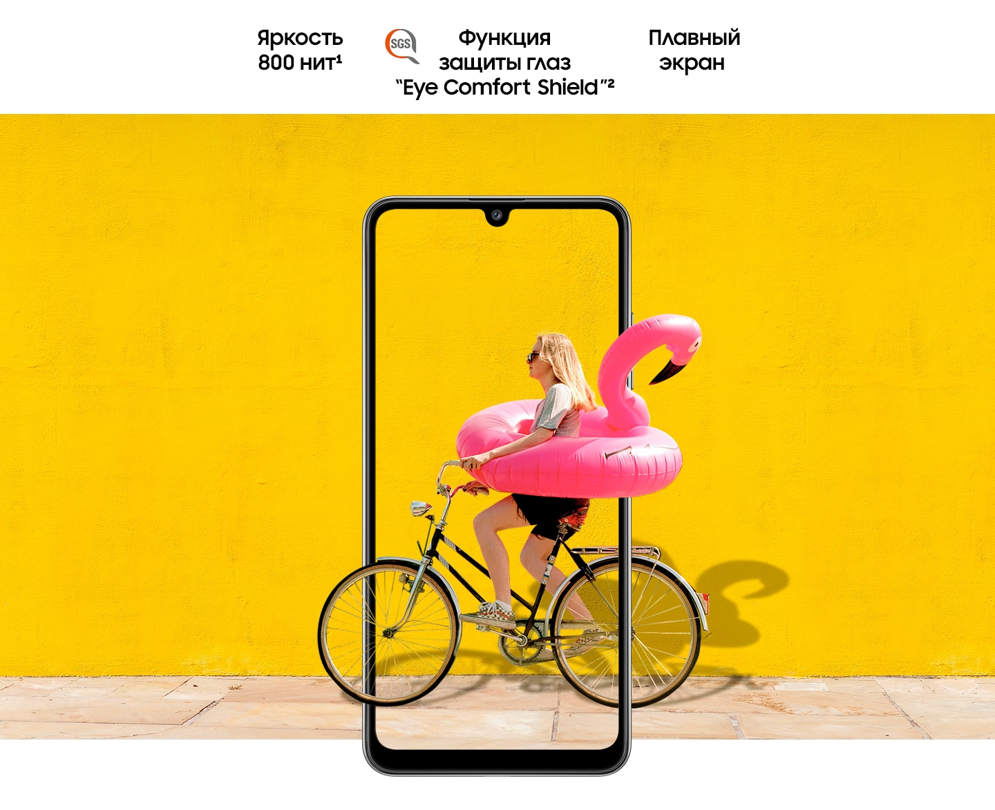 A woman on bike behind Galaxy A32. The picture goes the phone display's edges to represent its immersive view. Text says Brightness 800 nits, Eye Comfort Shield, with the SGS logo and Real Smooth.