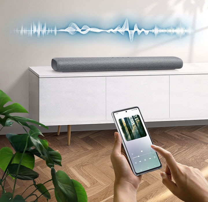 User plays music on their smartphone directly from their soundbar, which has soundwave graphics above it, using Music Mode which allows easy smartphone connectivity so optimized sound can be heard from soundbar.