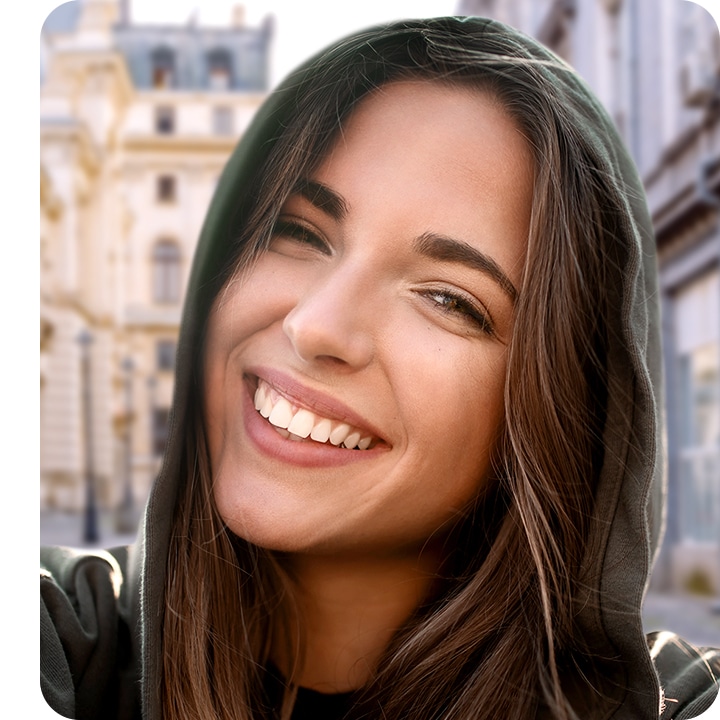 A woman looking в камеру, taking a selfie.  The background is subtly blurred out with the bokeh effect.