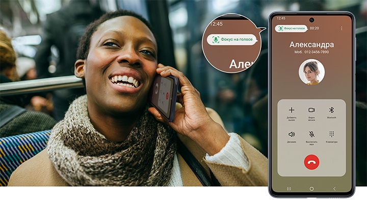 Женщина в автобусе, улыбаясь, отвечает на звонок со своего устройства M33 5G. Справа устройство Galaxy M33 5G показывает, что звонок от Кристины Адамс. Пузырь увеличения, расположенный в левом верхнем углу экрана, показывает, что функция активирована, и надпись "Голосовой фокус" выделена зеленым текстом.