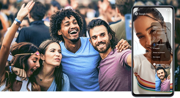 Группа друзей, улыбаясь и смеясь, разговаривает с другом в режиме видеозвонка с помощью устройства Galaxy M33 5G, которое держит друг в правом конце группы. Справа устройство M33 5G показывает человека, с которым они разговаривают во время видеозвонка, и показывает меню эффектов видеозвонка, которое указывает на активацию функции микрофонного режима.