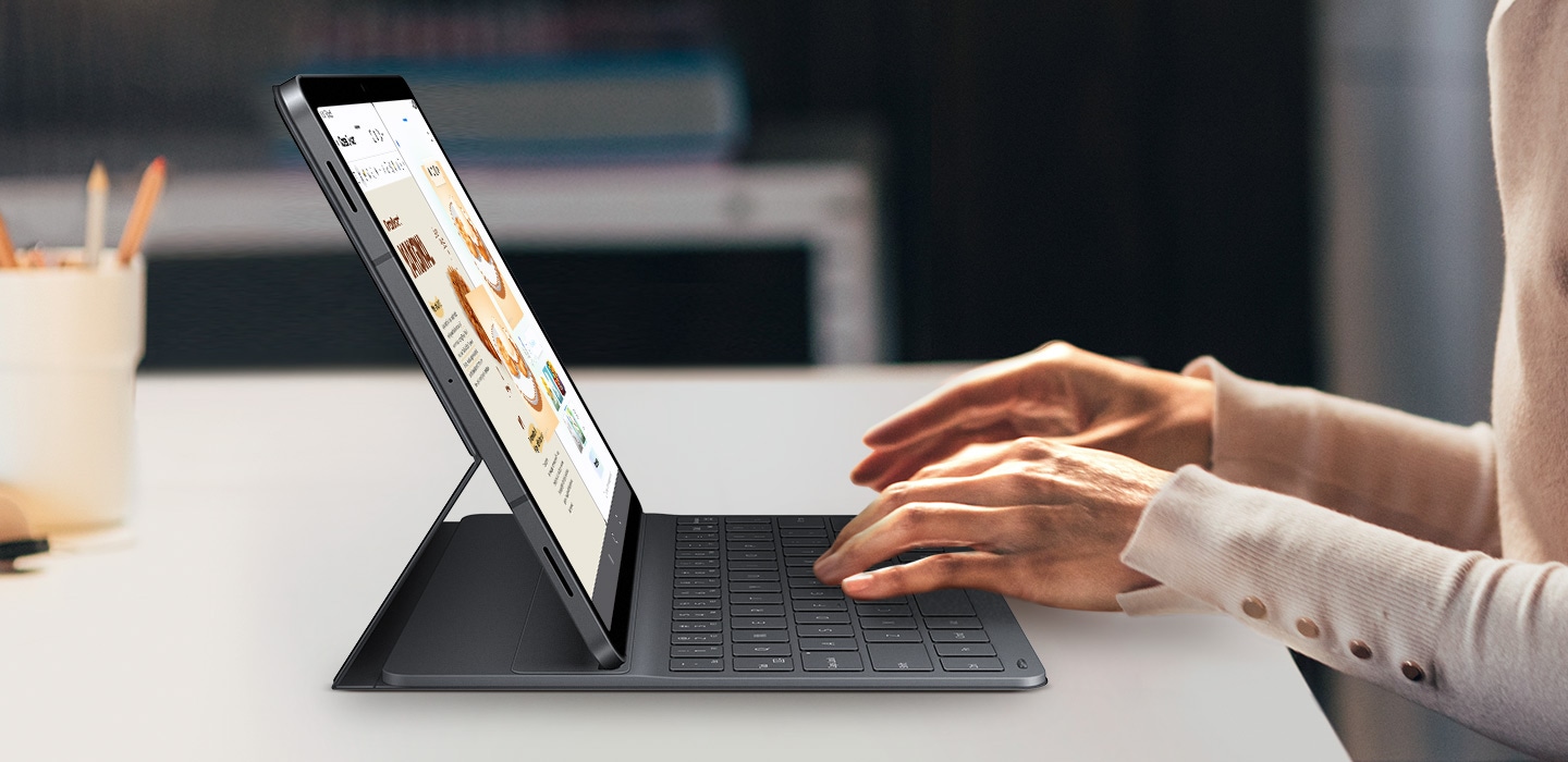 Человек использует планшет Galaxy Tab S11 с чехлом-клавиатурой Book Cover Keyboard Slim. На экране одновременно открыты приложения Drawing Assist и Samsung Notes. Элегантная клавиатура дополняет дизайн планшета, подчеркивая его безупречную профессиональную компоновку для выполнения множества творческих задач.