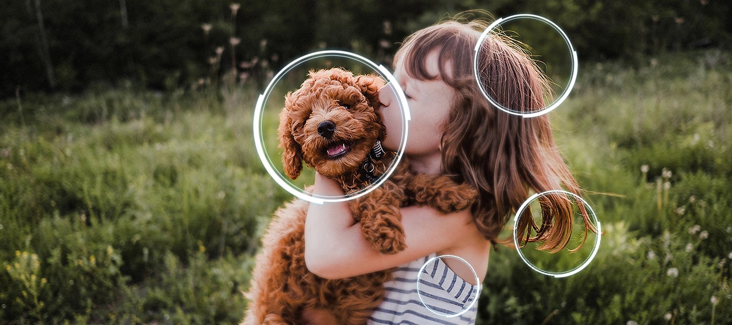 Image of a little girl kissing a puppy. The Samsung Micro RGB AI Engine processor appears on the photo and enhances several details, including the girl’s hair and clothes and the puppy’s face. The result is a much sharper image where subtle details are visible.
