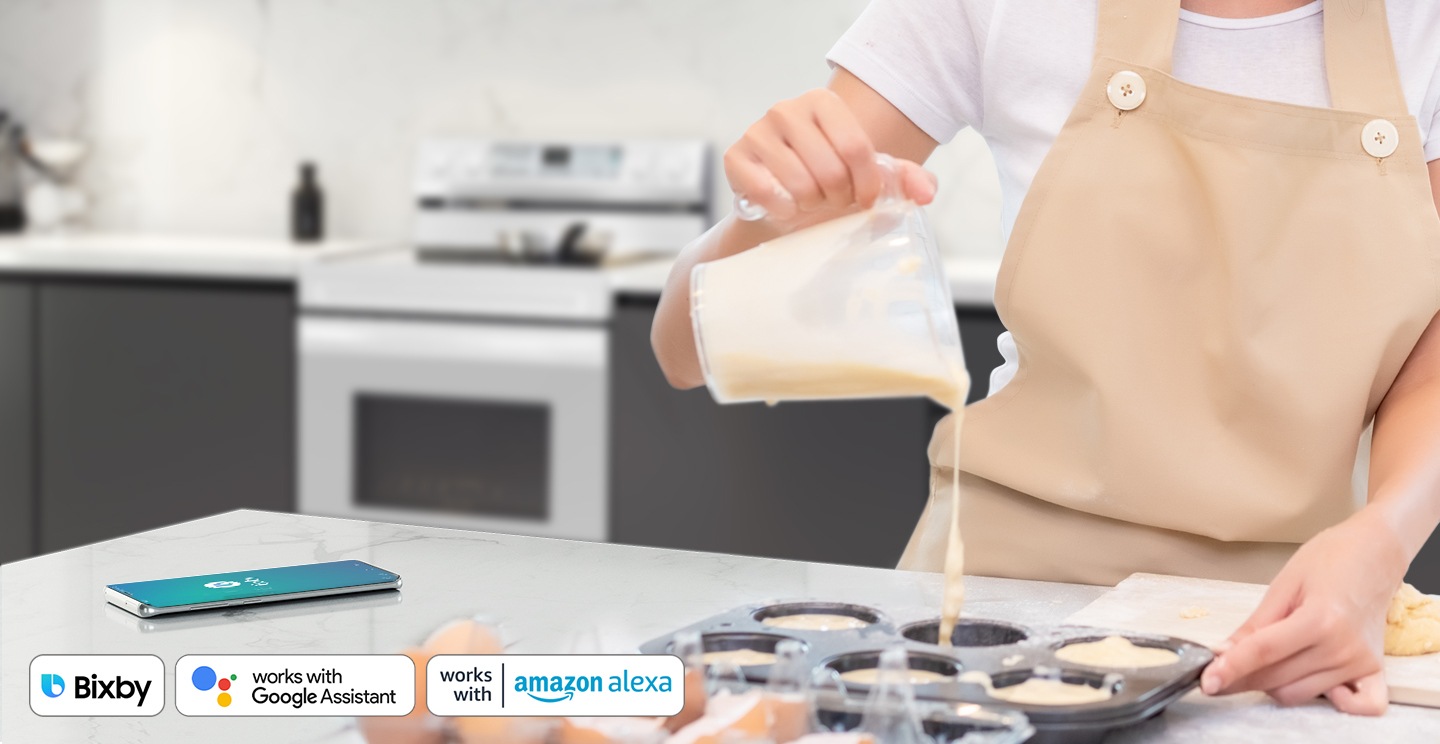 يظهر شخص يحضر معجنات عن طريق التحكم صوتياً بالفرن باستخدام تطبيق هاتف ذكي مثل Bixby وGoogle Assistant.