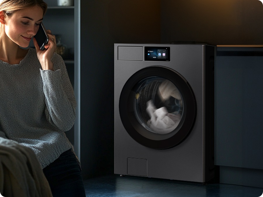 Inside the transparent washing machine, the drum shakes up and down. A vibration sensor located at the top scans the drum, while the damper is positioned at the bottom of the drum. A woman is on a phone call in front of the washer while it is running. * Images are for illustrative purposes only.