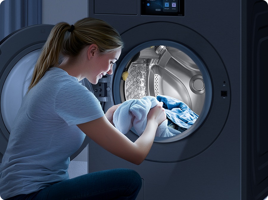 The interior light brightly illuminates the inside of the washing machine, making it easy for the woman to take out the laundry from the drum.