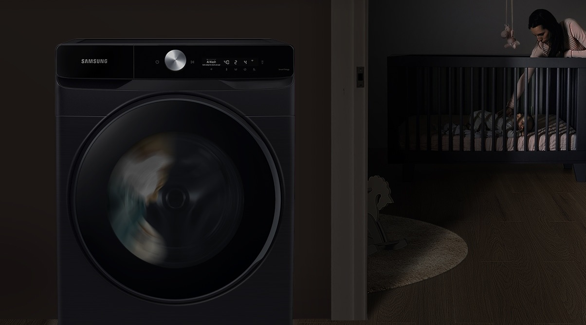 The mother puts the baby to sleep in the room at night, and the washer silently operates beside them.