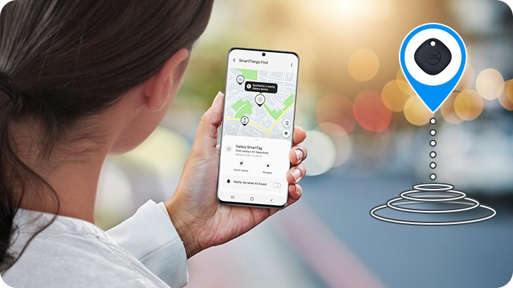 امرأة تتحقق من تطبيق الهاتف المتصل بجهاز Galaxy SmartTag لتتبع أغراضها؛ يُظهر التطبيق الموقع الذي يمكن العثور فيه على ما تفقده