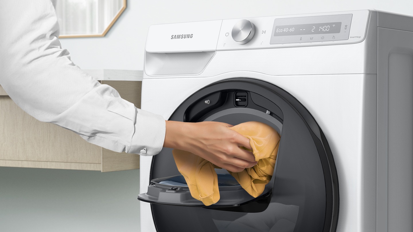 Extra laundry is added into the open Add Wash door by hand.