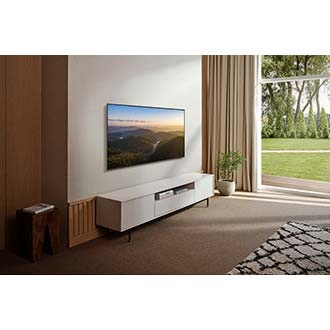 A QLED TV is hanging on a wall displaying blue graphic.