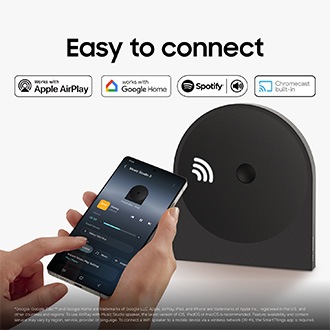 En person använder en smartphone för att trådlöst streama musik till Music Studio 5-högtalaren på ett skrivbord, vilket visar enkel Wi-Fi- och Bluetooth-anslutning för sömlös musikuppspelning.