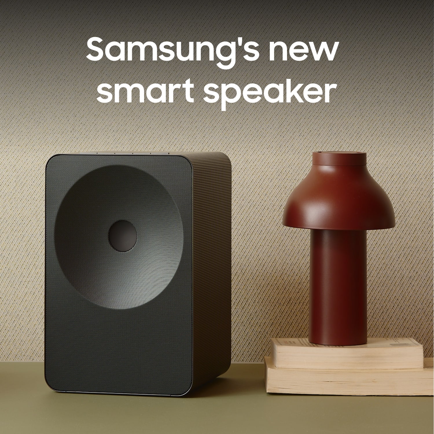 Music Studio 7 på ett bord med en lampa som står ovanpå två böcker. En text som säger "Samsungs nya smarta högtalare".