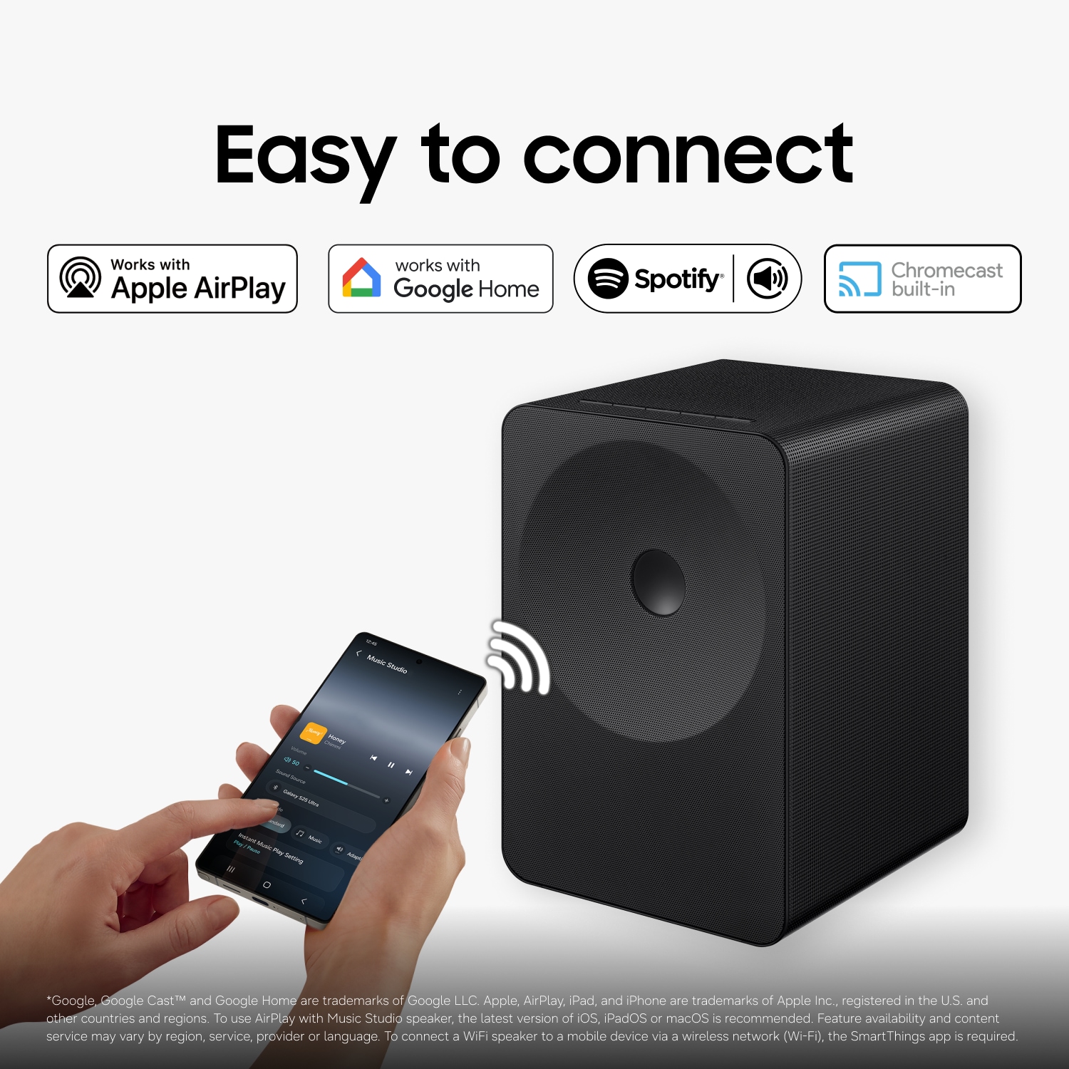 En person använder en smartphone för att trådlöst streama musik till Music Studio 7-högtalaren på ett skrivbord, vilket visar enkel Wi-Fi- och Bluetooth-anslutning för sömlös musikuppspelning.