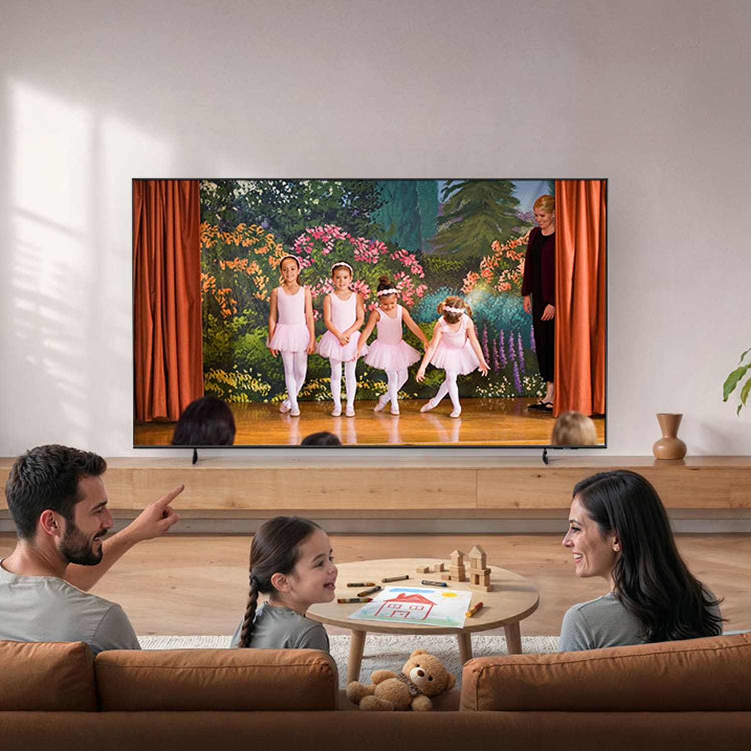 A family sits on a sofa watching a U7000H TV showing children performing a ballet recital, with toys and books scattered in a bright living room.