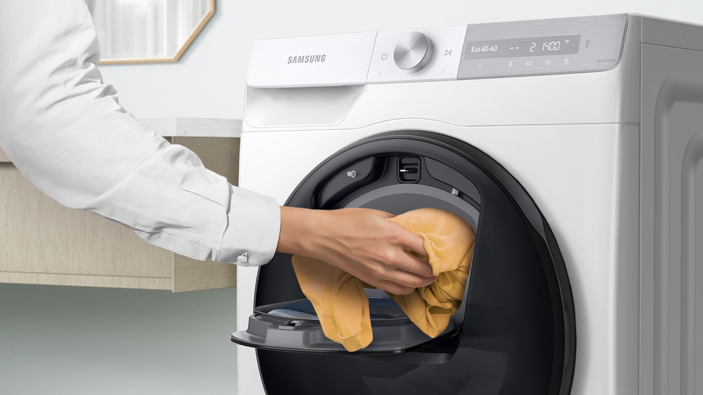 Get WW12TP94DSX/SP now. Woman seen adding laundry by hand through AddWash door QuickDrive™, 12Kg, Front Load, 4 Ticks