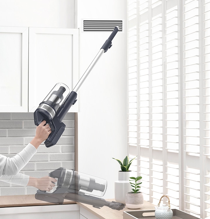 A person lifts the lightweight VS6700 with one hand to clean the high ventilation shaft with the extension crevice tool and cleans the tabletop with the combination tool.