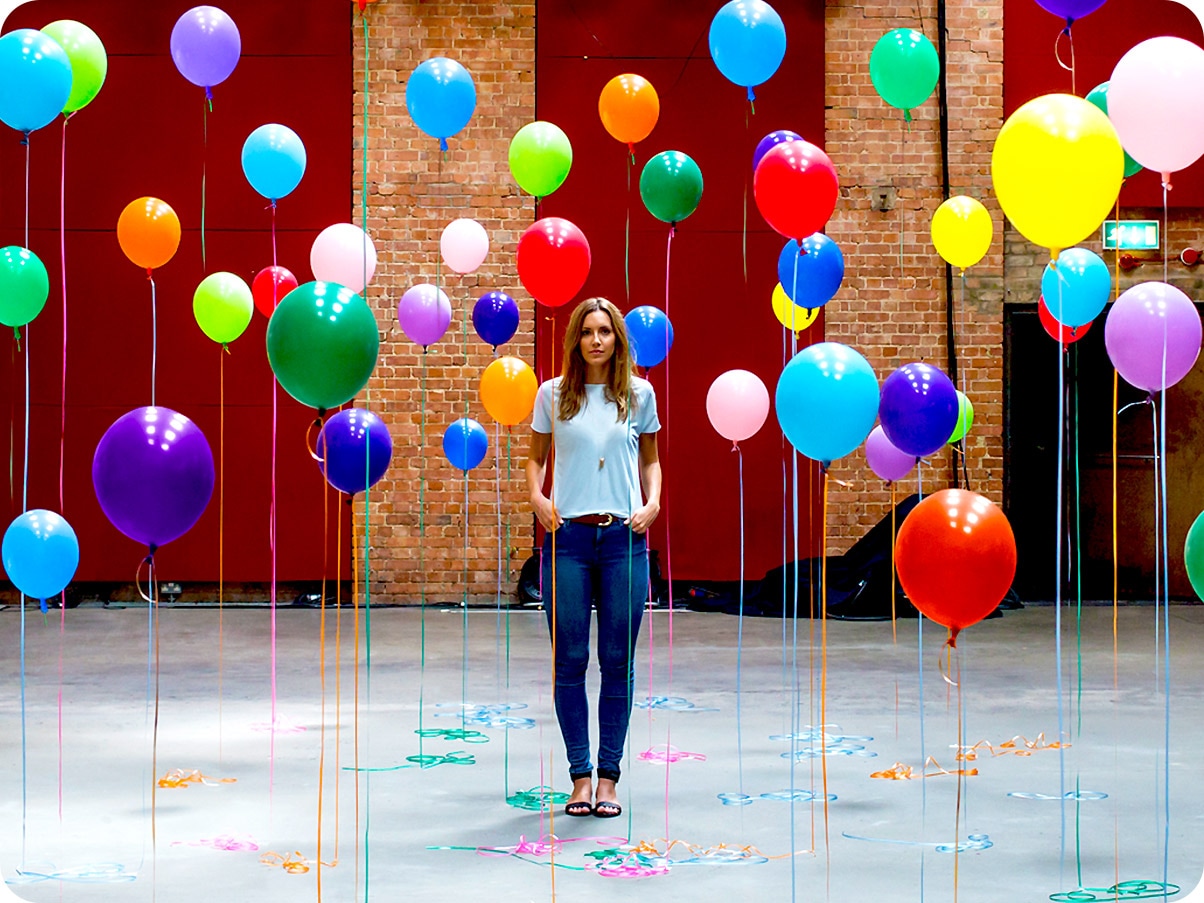 Samsung A22 5g wide angle camera taking a close-up shot of a woman standing in the middle of many different colour balloons.