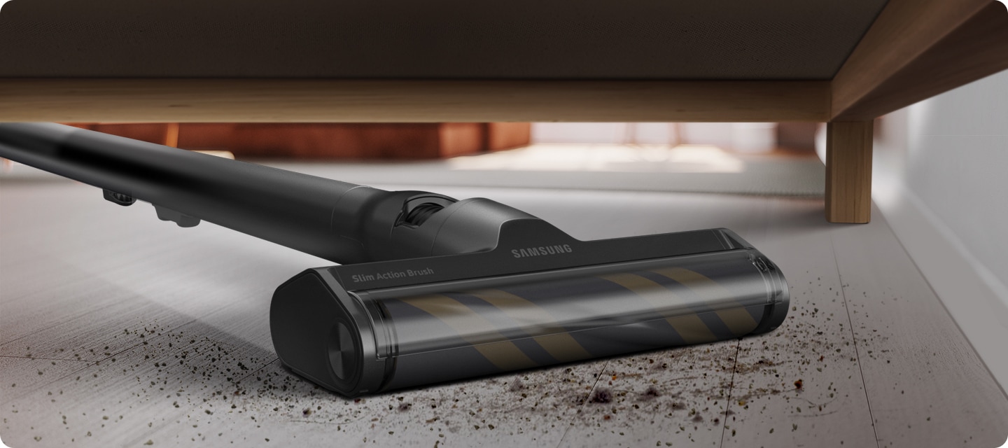 A Bespoke JET with a slim action brush attachment reaches underneath some furniture to vacuum dirt.