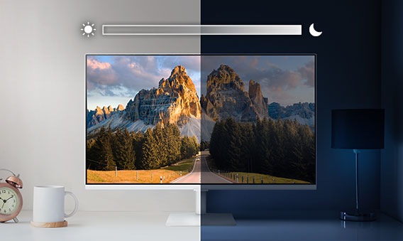 A monitor sits on top of a desk and is split into left and right sides. The left side is brightly lit while the right side is very dark. Above the screen is a slider icon with a sun on the left and a moon on the right.
