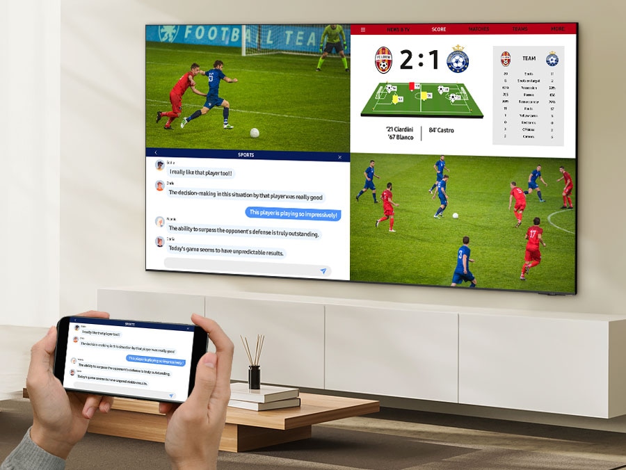 A person watches 4 different screens on their TV simultaneously. They have two screens displaying a soccer match from two different angles, the third screen displaying live stats and the last screen mirroring their mobile as they chat about the game.