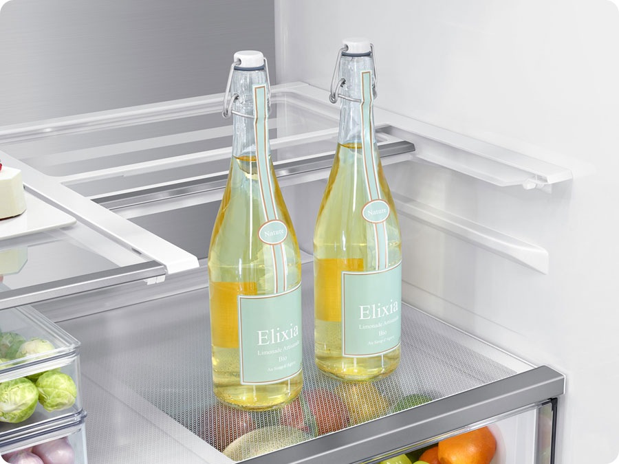 There is a closeup of a folded slide-in shelf inside the refrigerator. There are two tall glass bottles.