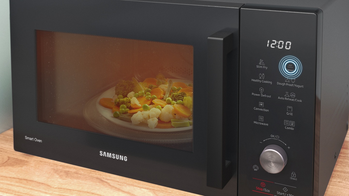 Shows the front of the microwave oven with a plate of vegetables being cooked inside. The position of the 'Sensor Cook' button on the control panel is highlighted.