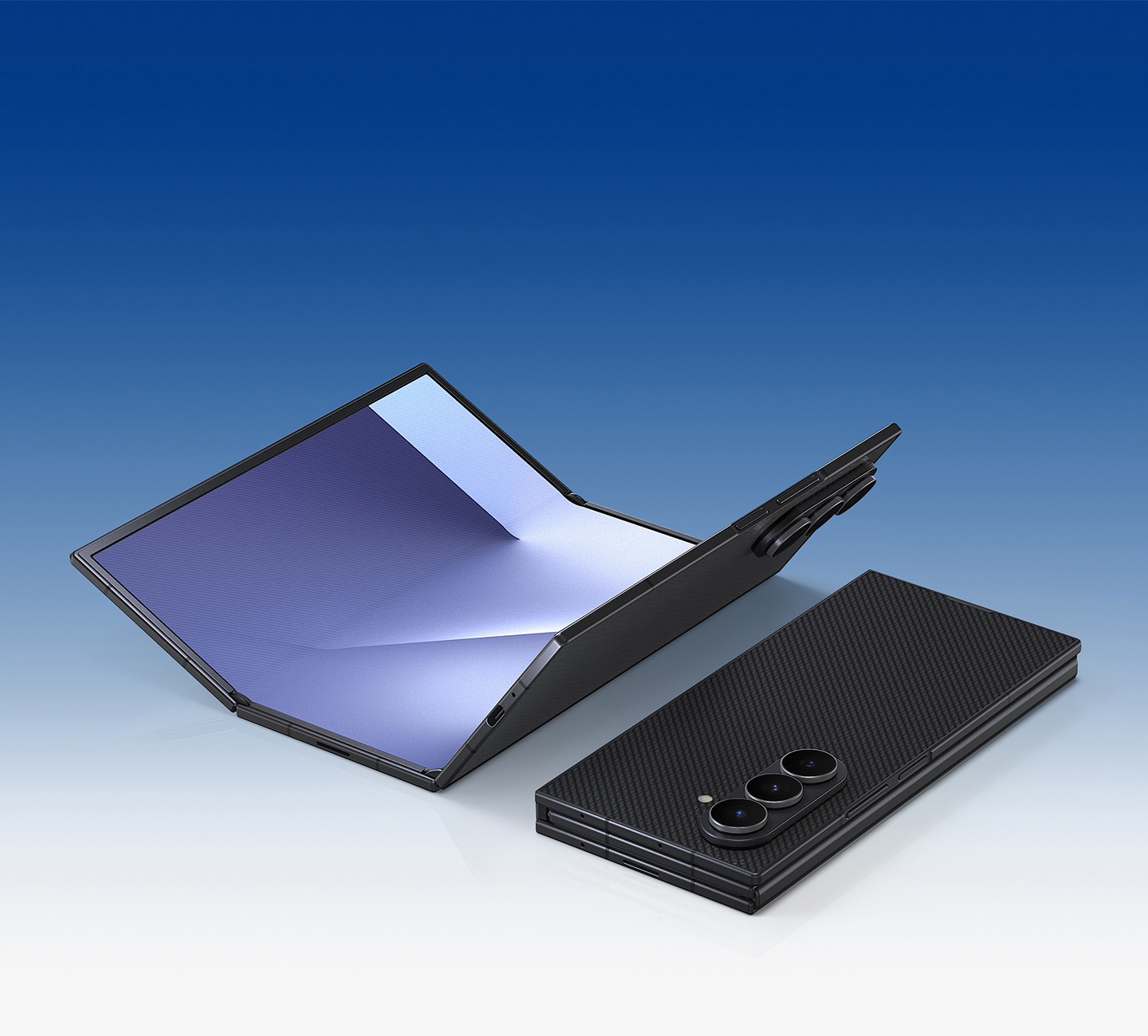 Two Galaxy Z TriFold devices are seen. One is mostly unfolded with the main screen facing up. The other is fully folded and seen from the rear to show its Crafted Black color.