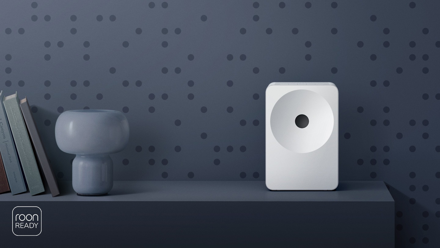 A minimalist shelf featuring Music Studio 7 speaker with a sculptural design, styled like an art object. Roon Ready logo.