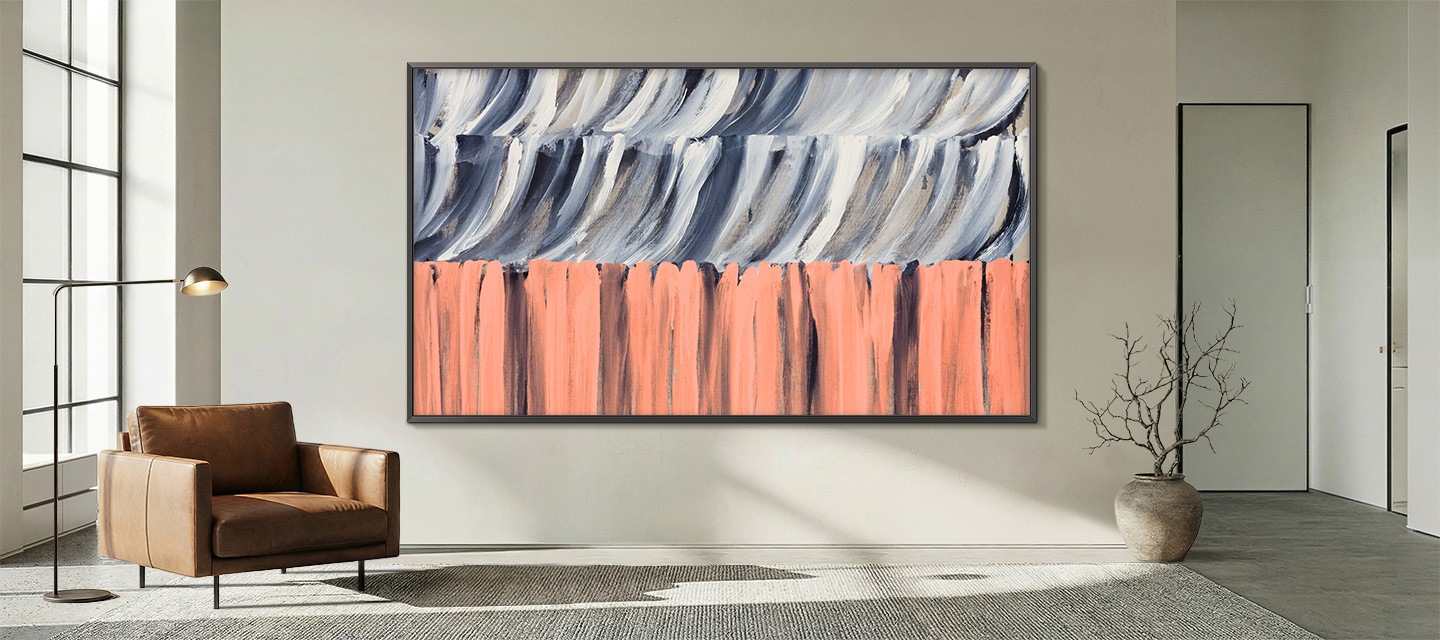 Minimalist living room with large window, leather armchair, and floor lamp, featuring The Frame TV mounted flush to the wall displaying abstract artwork, blending seamlessly like a framed painting.