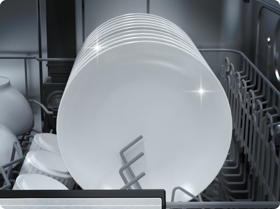 Close-up of dishes loaded inside the dishwasher. The dishes are thoroughly cleaned and shining.