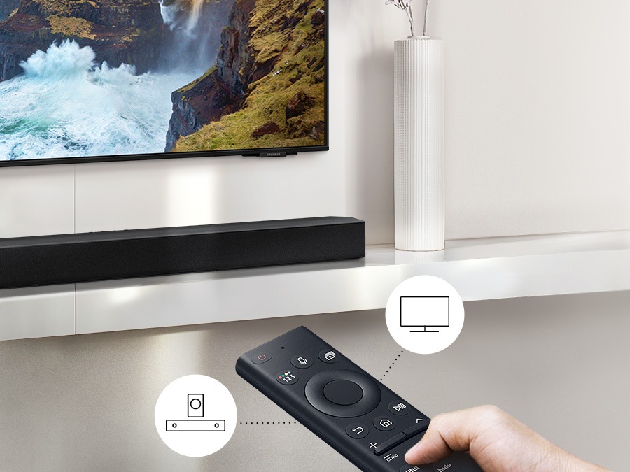 Користувач керує функціями звукової панелі та телевізора за допомогою пульта дистанційного керування телевізора Samsung.