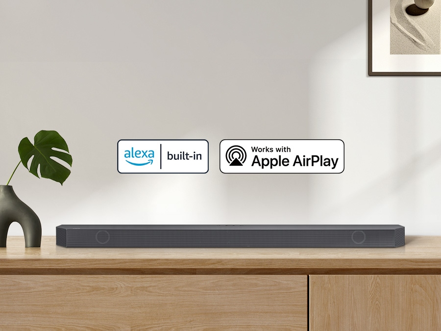 Alexa logo and Apple AirPlay logo can be seen along with Samsung Q800B soundbar which is sitting on living room cabinet.