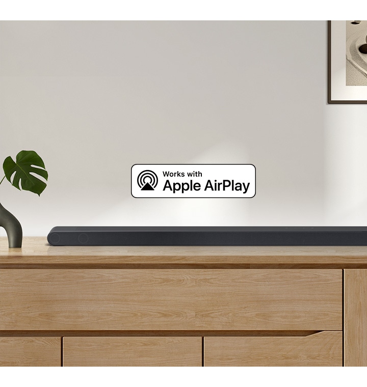 Zvočnik Samsung Soundbar stoji na vrhu omarice, spremlja ga logotip za Deluje z Apple AirPlay.