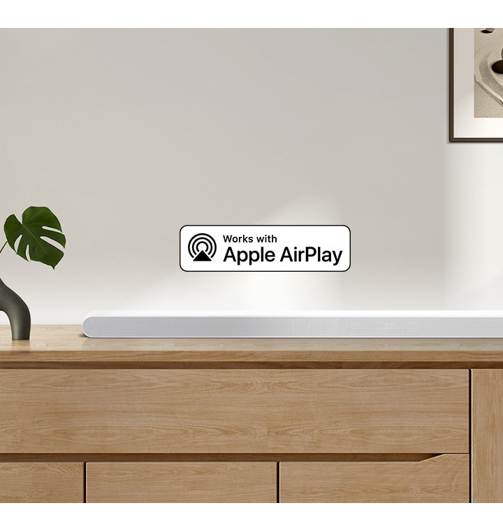 Zvočnik Samsung Soundbar stoji na vrhu omarice, spremlja ga logotip za Deluje z Apple AirPlay.