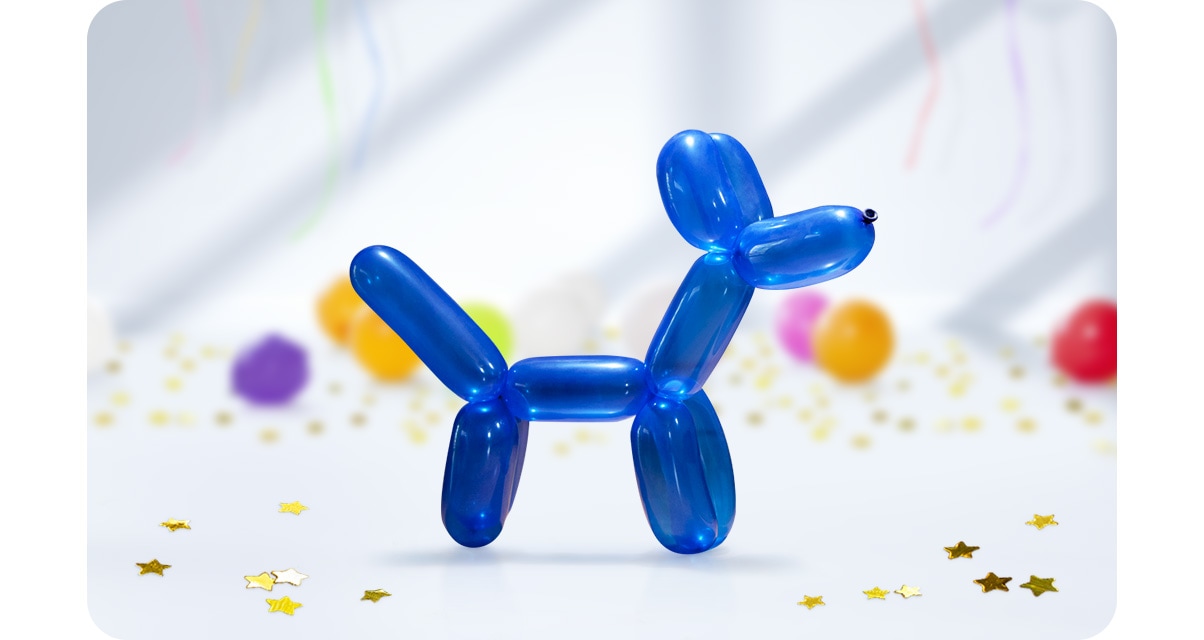 1. V popredí je umiestnený modrý balón v tvare psa, v pozadí vidíme ďalšie balóny a dekorácie. Len pes je zaostrený. 