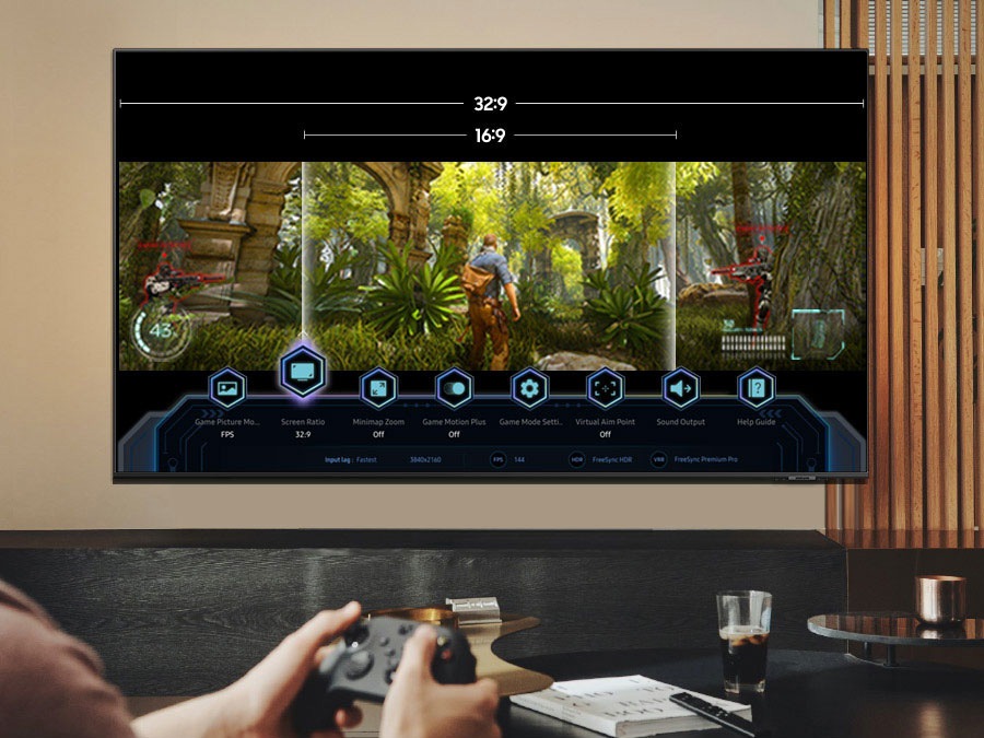 Людина, яка грає в гру на OLED-телевізорі, яка показує ігрову панель, і можливість перемикання між 32: 9 та 16:9.