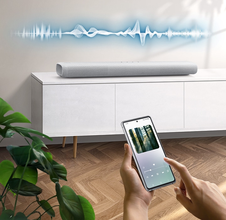 User plays music on their smartphone directly from their soundbar, which has soundwave graphics above it, using Music Mode which allows easy smartphone connectivity so optimized sound can be heard from soundbar.