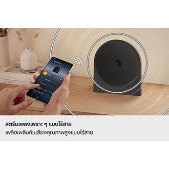 บุคคลหนึ่งใช้สมาร์ทโฟนเพื่อสตรีมเพลงแบบไร้สายไปยังลำโพง Music Studio 5 ที่วางอยู่บนโต๊ะ แสดงให้เห็นถึงการเชื่อมต่อ Wi-Fi และ Bluetooth ที่ง่ายดายเพื่อการเล่นเพลงที่ราบรื่น
