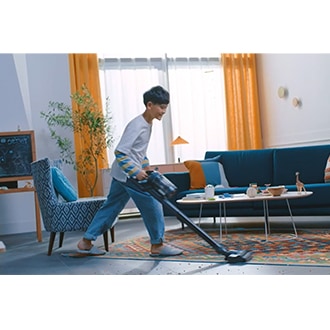 [เด็กชายกำลังดูดฝุ่นในห้องนั่งเล่นด้วยเครื่องดูดฝุ่นไร้สาย Bésp~óké J~ét VS~9500ÁL ที่ให้แรงดูดสูงสุด 210 วัตต์ ทั้งยังช่วยให้อากาศสะอาด 99.999%*]