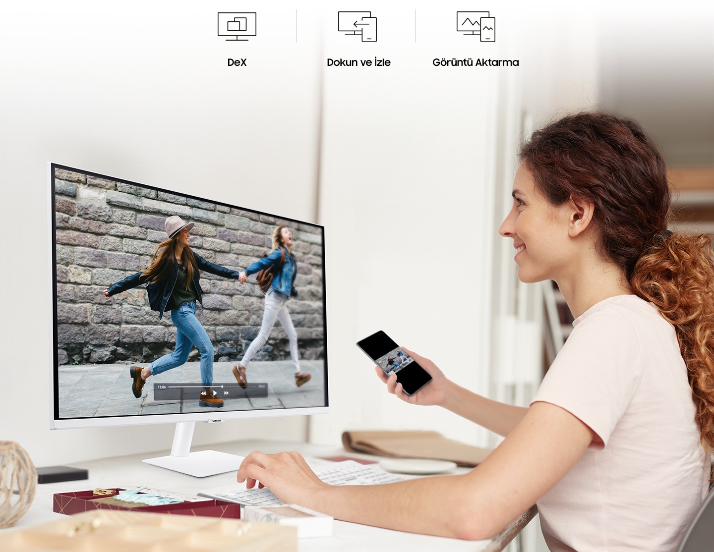 A smiling woman mirrors videos from her phone to her monitor. At the top are the DeX, Tap View, and Mirroring icons.