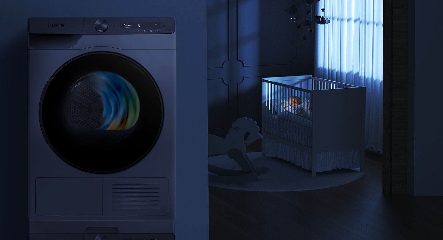 The baby on the bed sleeps beside the operating dryer in the dark room.