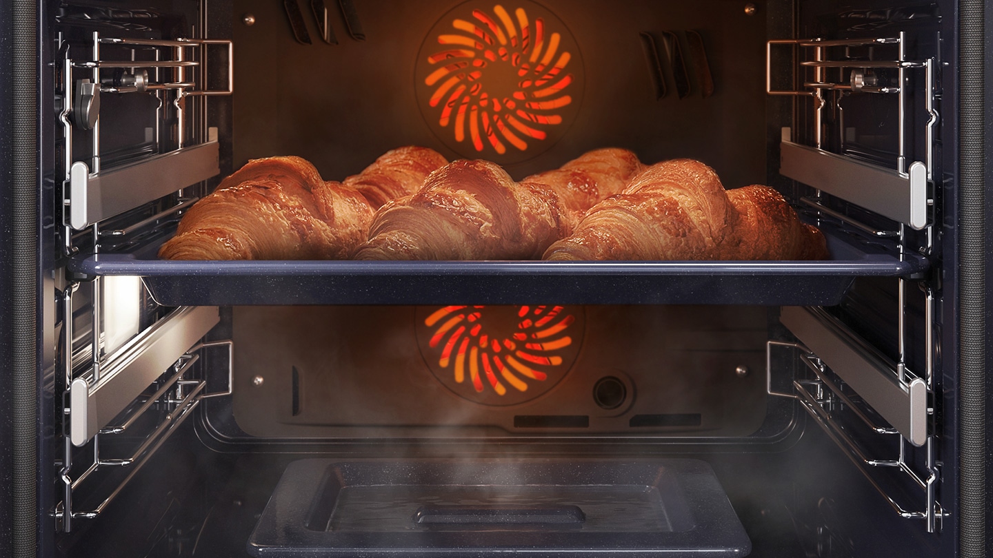 Shows a tray of croissants inside the oven being cooked using the convection system, while being surrounded by steam that is rising from a dedicated tray on the bottom of the oven.