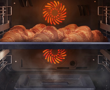 Shows a close-up of croissants being baked in the oven, but being kept moist with steam using the Natural Steam option.