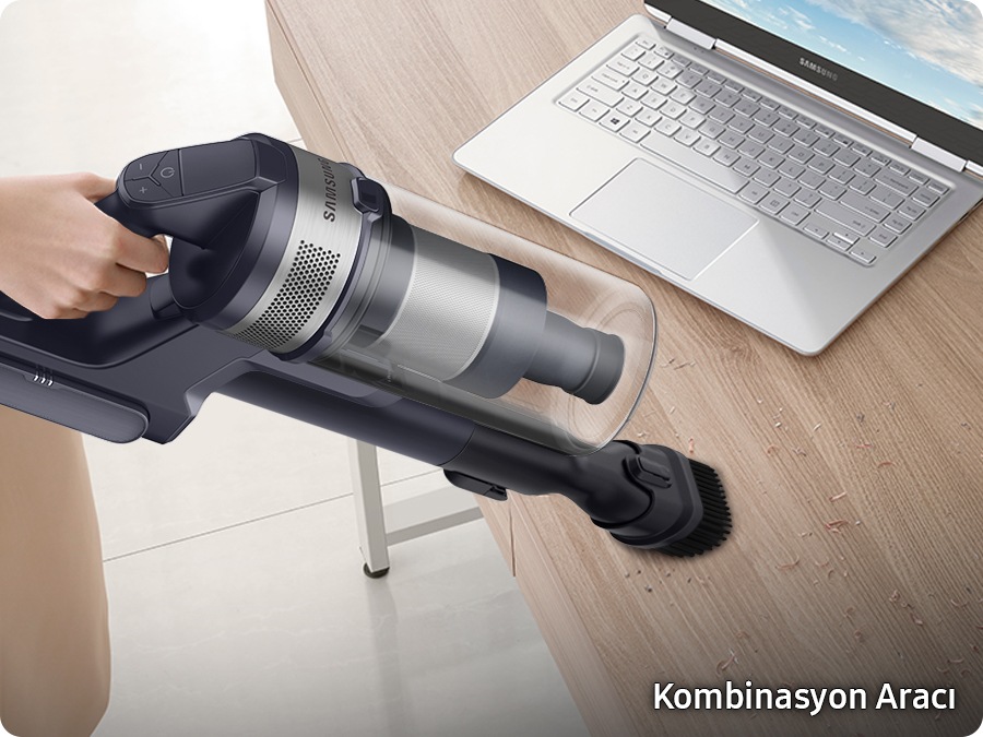 A Jet 75E with the combination tool cleans dirt on a desk near a laptop. 