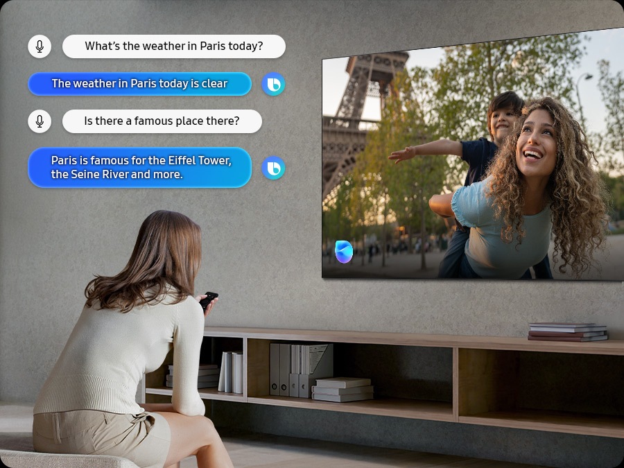 Woman in living room speaks to Bixby through the TV. Captions of the dialogue are shown. What’s the weather in Paris today? The weather in Paris today is clear. Is there a famous place there? Paris is famous for the Eiffel Tower, the Seine River and more.