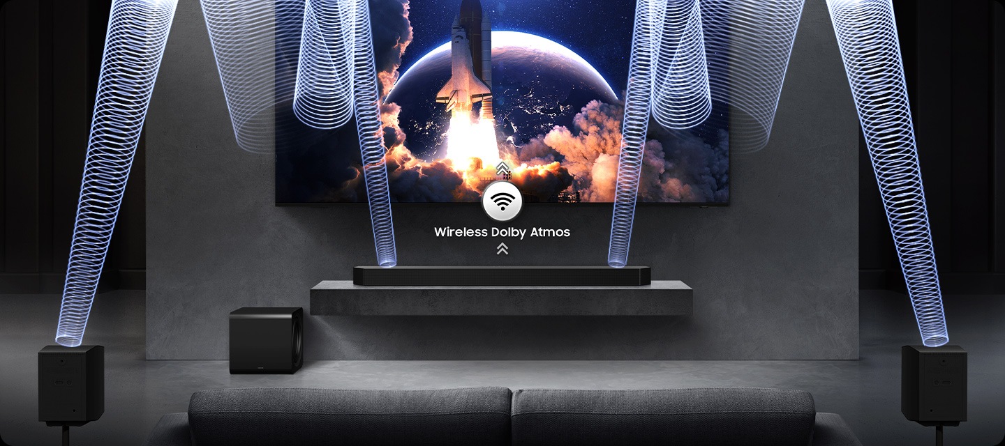 TV’nin altındaki soundbar’ın yakın çekimi. Kablosuz Dolby Atmos ve yukarıyı gösteren oklara sahip kablosuz simgesi. Soundbar, derin baslı hoparlör ve arka hoparlörleri içeren ses sistemiyle birlikte TV'nin tamamını göstermek için görüntüden uzaklaşılıyor. Soundbar ve arka hoparlörlerden yayılan ses dalgaları tavandan aşağıya doğru yansıyor.