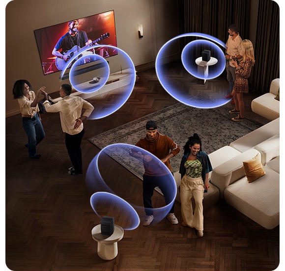 İnsanlar, odanın karşılıklı uçlarına yerleştirilmiş bir soundbar’dan ve arka hoparlörlerden gelen ses dalgaları yayılan bir odada dans ediyor.