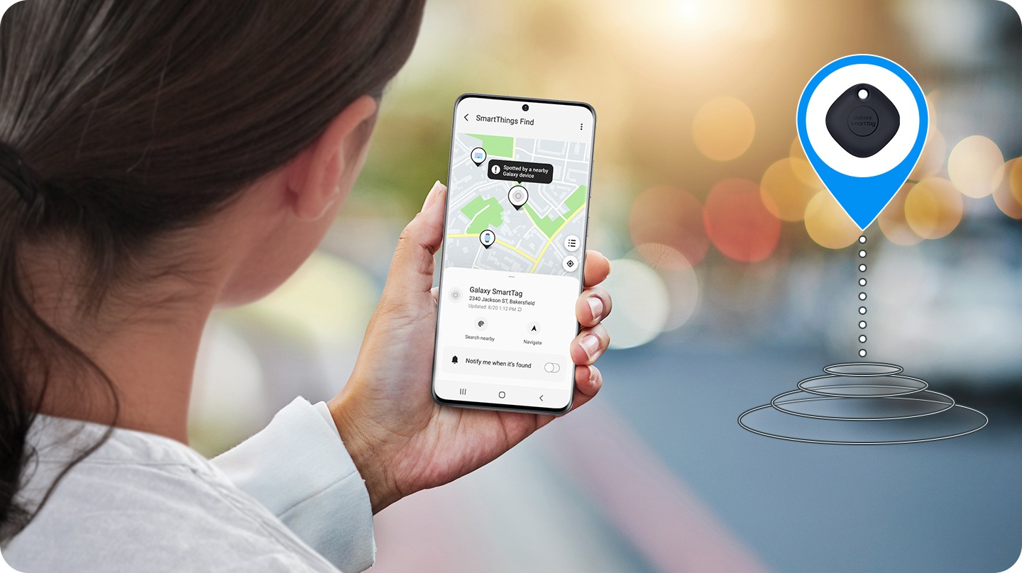 Bir kadın, eşyasının izini geriye doğru takip etmek için Galaxy SmartTag’e bağlanmış mobil uygulamayı kontrol etmekte. Uygulama eşyanın bulunabileceği konumu göstermekte